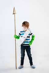 Image showing Little caucasian boy as a warrior in fight with coronavirus pandemic, with a face mask, a spear and a toilet paper bandoleer, serious