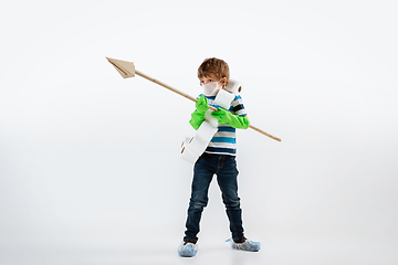 Image showing Little caucasian boy as a warrior in fight with coronavirus pandemic, with a face mask, a spear and a toilet paper bandoleer, attacking