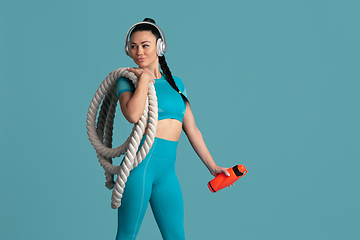 Image showing Beautiful young female athlete practicing on blue studio background, monochrome portrait