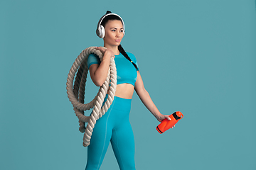 Image showing Beautiful young female athlete practicing on blue studio background, monochrome portrait