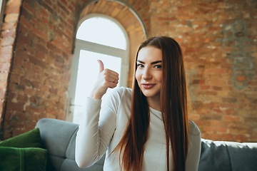 Image showing Caucasian woman isolated on brick wall background at home quarantined, cheerful and happy