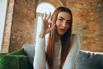 Image showing Caucasian woman isolated on brick wall background at home quarantined, cheerful and happy