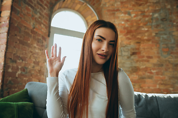 Image showing Caucasian woman isolated on brick wall background at home quarantined, cheerful and happy