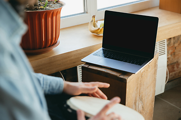 Image showing Caucasian musician playing hand drum during online concert at home isolated and quarantined, close up, blank laptop screen, copyspace