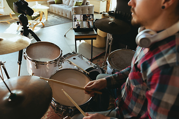 Image showing Caucasian musician playing drumms during online concert or sound-check with the band at home isolated and quarantined, focus on laptop