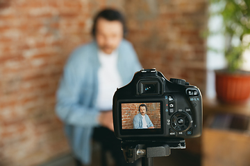 Image showing Caucasian musician playing hand drum during online concert at home isolated and quarantined, focus on camera