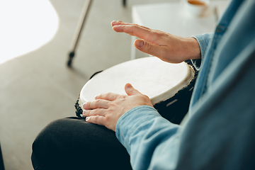 Image showing Caucasian musician playing hand drum during online concert at home isolated and quarantined, close up