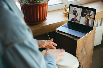 Image showing Caucasian musician playing hand drum during concert at home isolated and quarantined, playing with the band in online streaming, conference