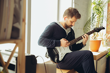 Image showing Caucasian musician playing guitar during online concert at home isolated and quarantined, cheerful improvising