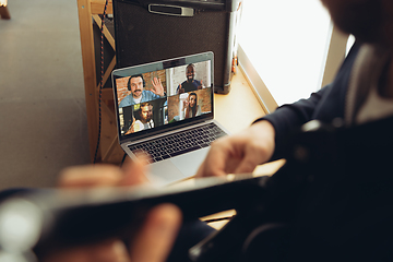 Image showing Caucasian musician playing guitar during concert at home isolated and quarantined, cheerful improvising with the band connected online