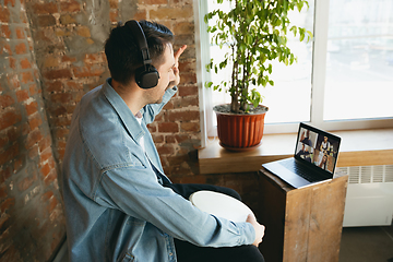 Image showing Caucasian musician playing hand drum during concert at home isolated and quarantined, playing with the band in online streaming, conference