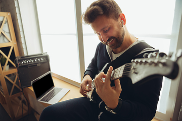 Image showing Caucasian musician playing guitar during online concert at home isolated and quarantined, cheerful improvising