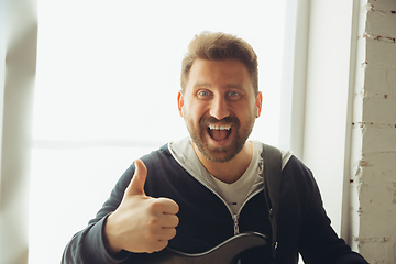 Image showing Caucasian musician greeting audience during concert at home isolated and quarantined, smiling, cheerful