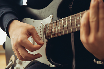 Image showing Caucasian musician playing guitar during concert at home isolated and quarantined, cheerful improvising, close up