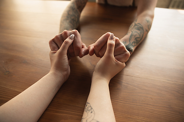 Image showing Loving couple holding hands close-up on wooden background, romantic