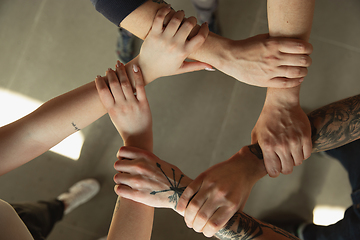 Image showing Close up of caucasian male and female hands, covering one another, team, friendship, business