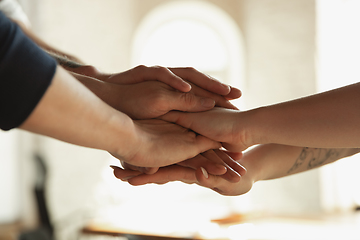 Image showing Close up of caucasian male and female hands, covering one another, team, friendship, business