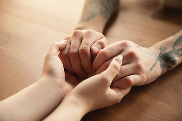 Image showing Loving couple holding hands close-up on wooden background, romantic