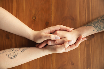 Image showing Loving couple holding hands close-up on wooden background, romantic