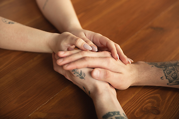 Image showing Loving couple holding hands close-up on wooden background, romantic