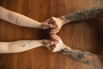 Image showing Loving couple holding hands close-up on wooden background, romantic