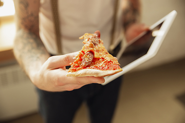 Image showing Close up of male hands holding pizza and tablet, proposing