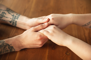 Image showing Loving couple holding hands close-up on wooden background, romantic