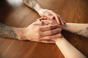 Image showing Loving couple holding hands close-up on wooden background, romantic