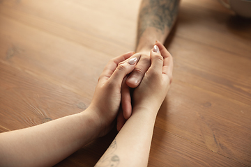 Image showing Loving couple holding hands close-up on wooden background, romantic