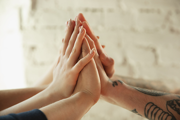 Image showing Close up of caucasian male and female hands, covering one another, team, friendship, business