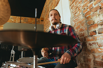 Image showing Caucasian musician playing drumms during online concert with the band at home isolated and quarantined, inspired improvising, close up