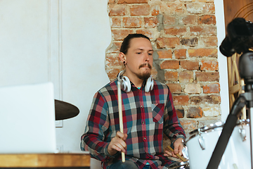 Image showing Caucasian musician playing drumms during online concert with the band at home isolated and quarantined, inspired improvising