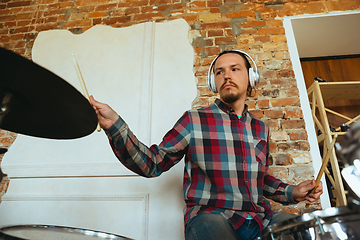 Image showing Caucasian musician playing drumms during online concert with the band at home isolated and quarantined, inspired improvising