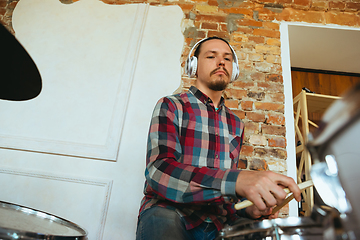 Image showing Caucasian musician playing drumms during online concert with the band at home isolated and quarantined, inspired improvising