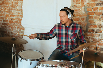 Image showing Caucasian musician playing drumms during online concert with the band at home isolated and quarantined, inspired improvising