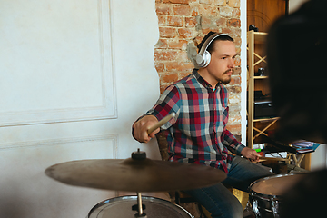 Image showing Caucasian musician playing drumms during online concert with the band at home isolated and quarantined, inspired improvising