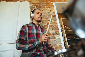 Image showing Caucasian musician playing drumms during online concert with the band at home isolated and quarantined, inspired improvising