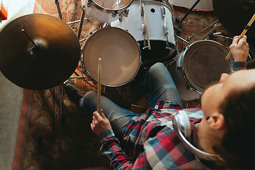 Image showing Caucasian musician playing drumms during online concert with the band at home isolated and quarantined, inspired improvising, close up