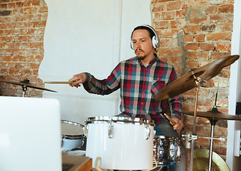 Image showing Caucasian musician playing drumms during online concert with the band at home isolated and quarantined, inspired improvising