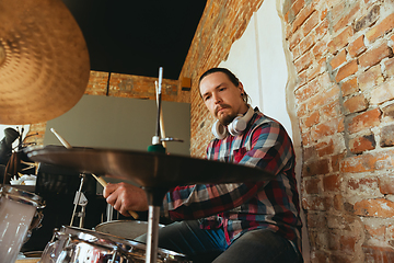 Image showing Caucasian musician playing drumms during online concert with the band at home isolated and quarantined, inspired improvising, close up