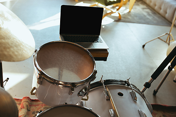 Image showing Caucasian musician playing drumms during online concert with the band at home isolated and quarantined, focus on blank laptop screen