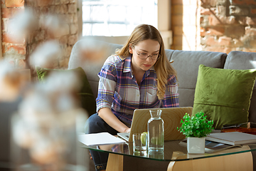 Image showing Young woman studying at home during online courses or free information by herself, making notes