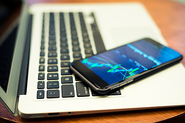 Image showing Laptop computer and cellphone with Stock market chart 