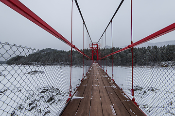 Image showing Suspension hanging bridge above winter frozen river