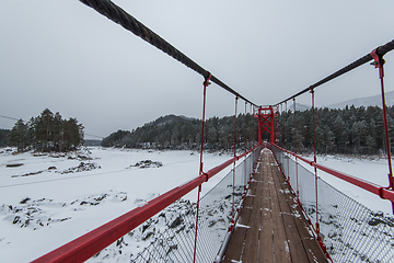 Image showing Suspension hanging bridge above winter frozen river