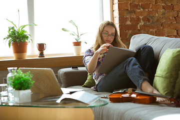 Image showing Young woman studying at home during online courses or free information by herself, making notes