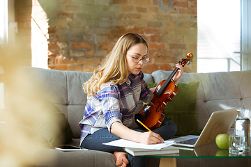 Image showing Young woman studying at home during online courses or free information by herself, making notes