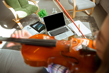 Image showing Young woman studying at home during online courses or free information by herself, playing violin, improvising