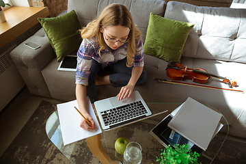 Image showing Young woman studying at home during online courses or free information by herself, making notes