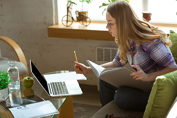 Image showing Young woman studying at home during online courses or free information by herself, making notes